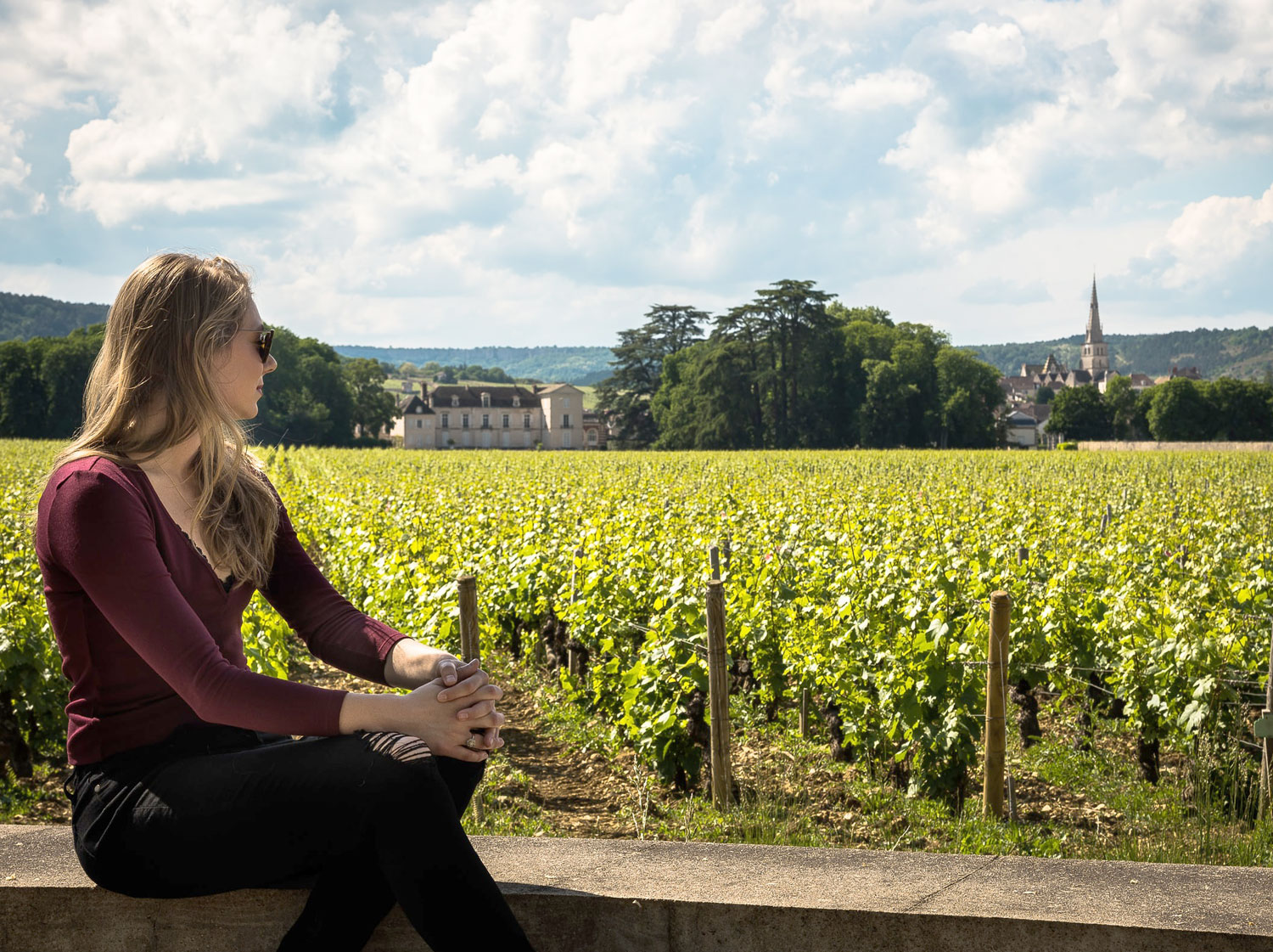 A woman sitting on a wall in a french vineyard