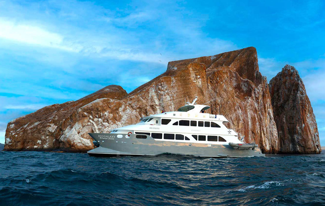 Luxury catamaran near rocky coastline