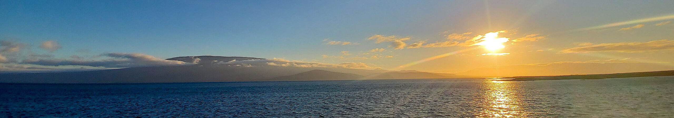 Orange sun setting over and island in Galapagos